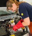 Auszubildende arbeitet an einem KFZ mit Hochvolttechnik