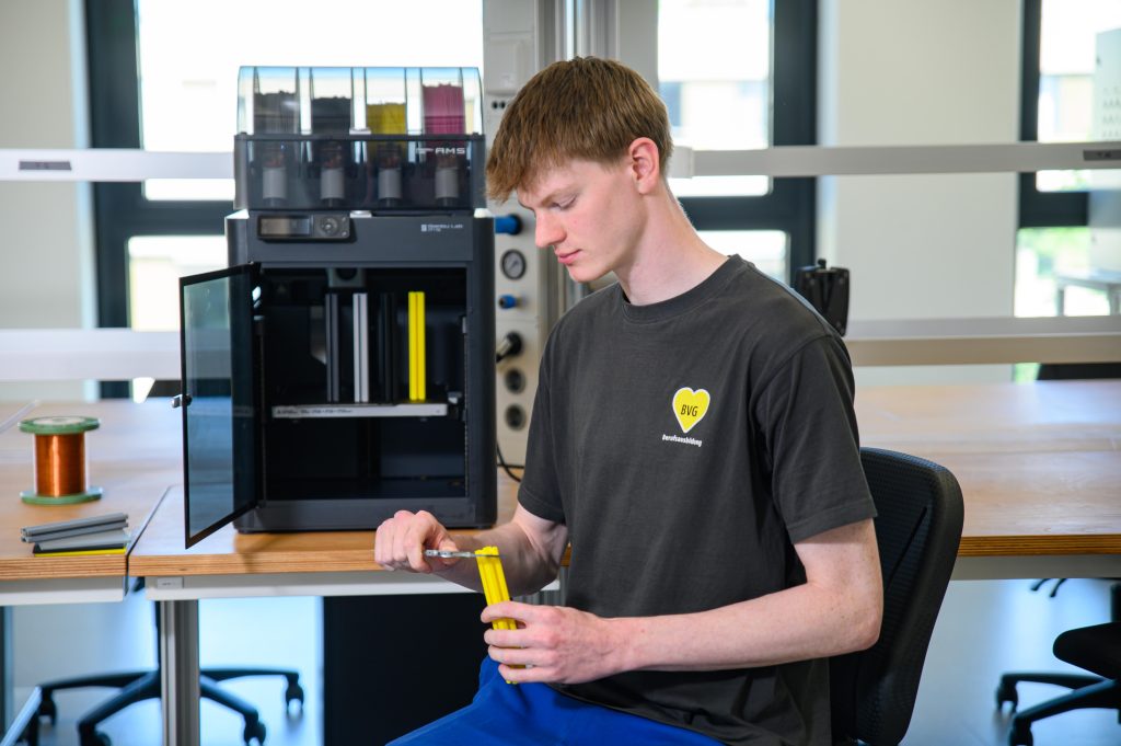 Auszubildender vermisst gedruckte Teile am 3D-Drucker.