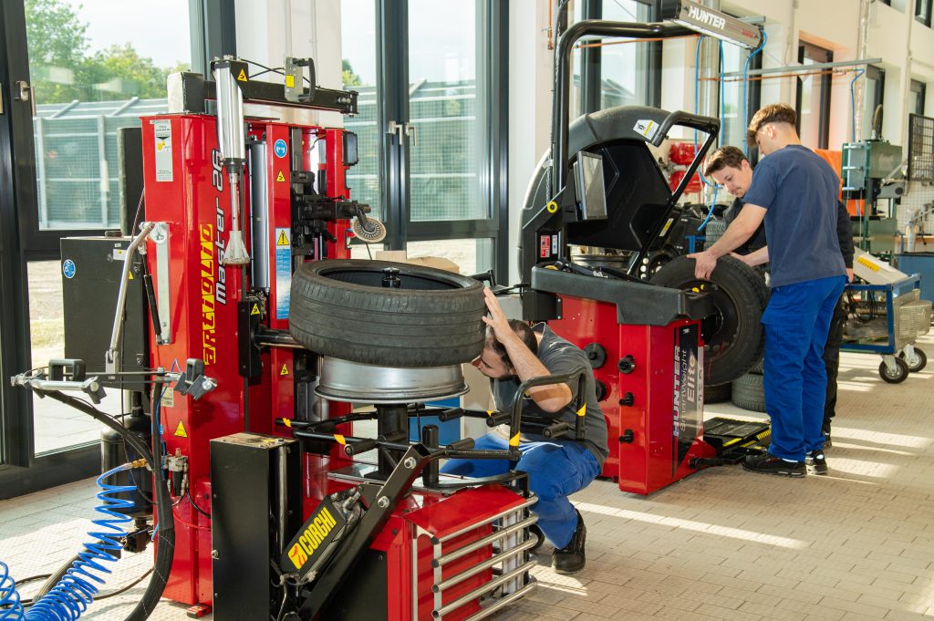 Auszubildende arbeiten an der Reifenmontiermaschine